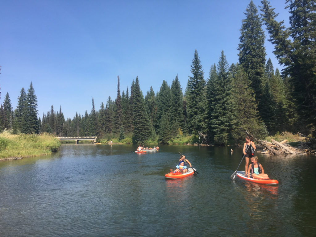 Paddle boarders in McCall Idaho float passed a bridge on the Payette River.